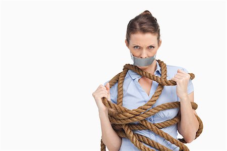 Businesswoman trying to untie herself against a white background Stock Photo - Premium Royalty-Free, Code: 6109-06005680