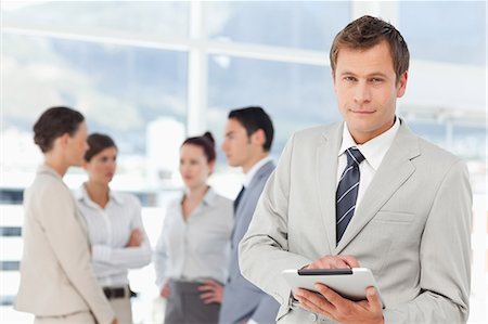 représentant (commerce) - Jeune vendeur avec tablet PC et ses collègues derrière lui Photographie de stock - Premium Libres de Droits, Code: 6109-06005681