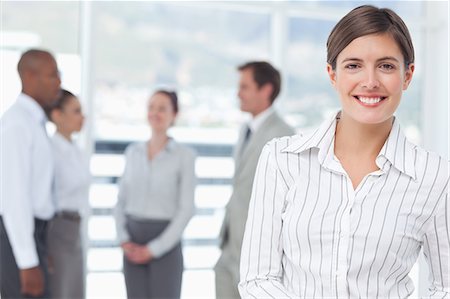 simsearch:6109-06005753,k - Smiling young saleswoman with colleagues behind her Stock Photo - Premium Royalty-Free, Code: 6109-06005698