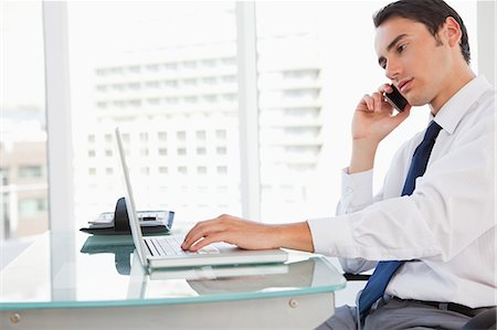 smart businessman - Businessman calling while tapping his laptop in a bright office Stock Photo - Premium Royalty-Free, Code: 6109-06005604