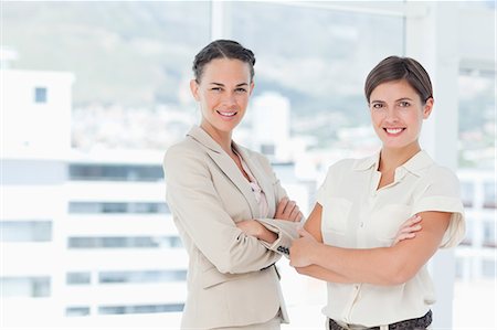 employee smiling - Smiling businesswomen with their arms folded next to a window Stock Photo - Premium Royalty-Free, Code: 6109-06005636