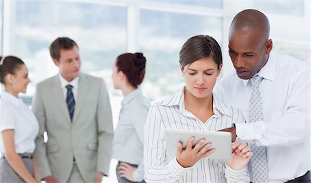 Young salesman showing his colleague how to use a tablet Stock Photo - Premium Royalty-Free, Code: 6109-06005753