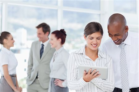 sales person with a tablet - Smiling young salespeople looking at tablet computer Stock Photo - Premium Royalty-Free, Code: 6109-06005754