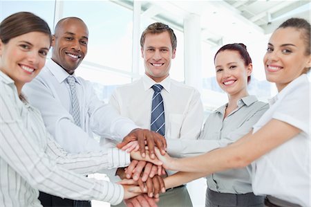 pictures of hands and arms united - Smiling young businessteam doing teamwork gesture Stock Photo - Premium Royalty-Free, Code: 6109-06005787