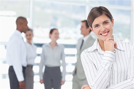 simsearch:6109-06005762,k - Thoughtful smiling young saleswoman with colleagues behind her Stock Photo - Premium Royalty-Free, Code: 6109-06005703