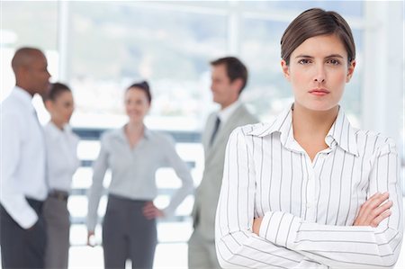 personnel (employé) - Jeune vendeuse avec les bras croisés et collègues derrière elle Photographie de stock - Premium Libres de Droits, Code: 6109-06005705