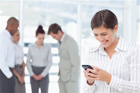 simsearch:6109-06005786,k - Smiling young saleswoman with cellphone and colleagues behind her Foto de stock - Royalty Free Premium, Número: 6109-06005706