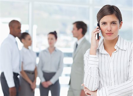 représentant (commerce) - Jeune vendeuse sur son téléphone cellulaire et d'associés derrière elle Photographie de stock - Premium Libres de Droits, Code: 6109-06005715