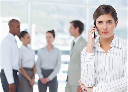 sales representative not headset - Young saleswoman on her cellphone and associates behind her Stock Photo - Premium Royalty-Free, Code: 6109-06005715