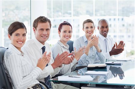 smiling corporate man woman - Side view of applauding young salesteam sitting at a table Stock Photo - Premium Royalty-Free, Code: 6109-06005843