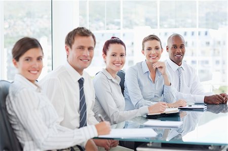 Side view of smiling young businesspeople sitting at a table Stock Photo - Premium Royalty-Free, Code: 6109-06005841