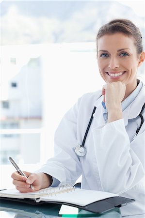 Smiling female doctor taking notes on her pocket calendar Stock Photo - Premium Royalty-Free, Code: 6109-06005865