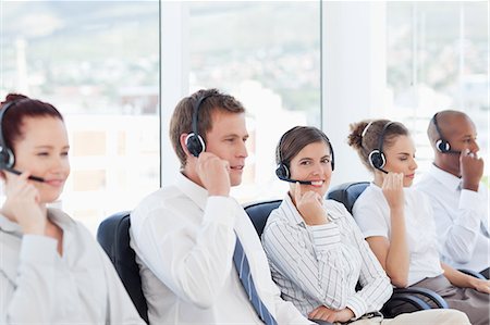 simsearch:6109-06005806,k - Smiling young call center agent sitting among her colleagues Stock Photo - Premium Royalty-Free, Code: 6109-06005803
