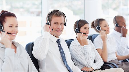 simsearch:6109-06005809,k - Smiling young call center agent sitting in between his colleagues Stock Photo - Premium Royalty-Free, Code: 6109-06005802