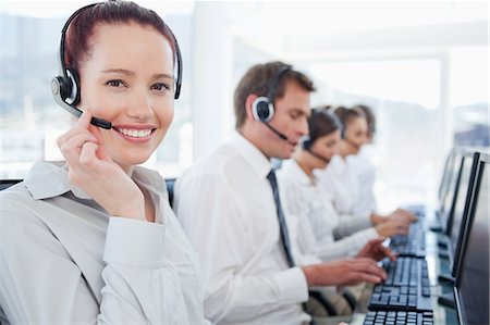 simsearch:6109-06005806,k - Smiling young call center agent with her colleagues behind her Stock Photo - Premium Royalty-Free, Code: 6109-06005809