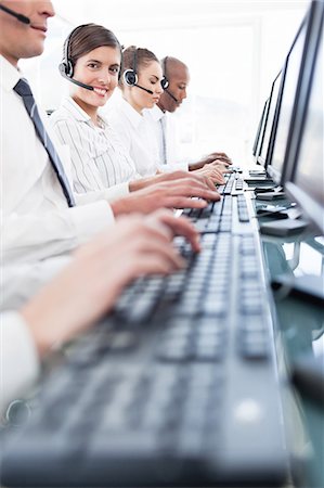 Smiling young call center employee sitting among her colleagues Stock Photo - Premium Royalty-Free, Code: 6109-06005821