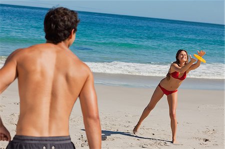 Frau Fang ein Frisbee am Strand mit ihrem Freund im Vordergrund und das Meer im Hintergrund Stockbilder - Premium RF Lizenzfrei, Bildnummer: 6109-06005976