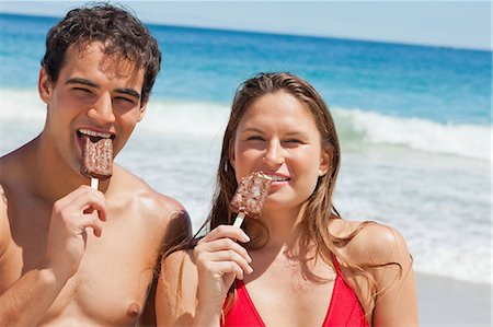 Portrait d'amoureux en maillot de bain manger Popsicle ainsi que de la mer en arrière-plan Photographie de stock - Premium Libres de Droits, Code: 6109-06006074