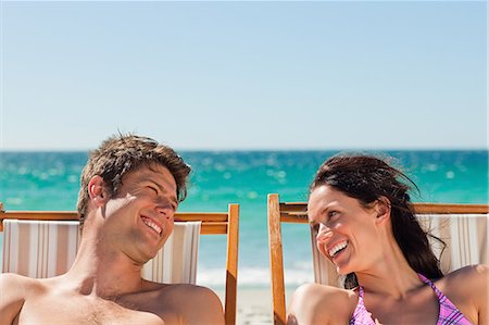 simsearch:6109-06006157,k - Close-up of lovers laughing while taking a sunbath with the ocean in background Stock Photo - Premium Royalty-Free, Code: 6109-06006144