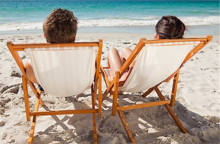 simsearch:6109-06006157,k - Rear view of a couple taking a sunbath on deck chairs in front of the ocean Stock Photo - Premium Royalty-Free, Code: 6109-06006148