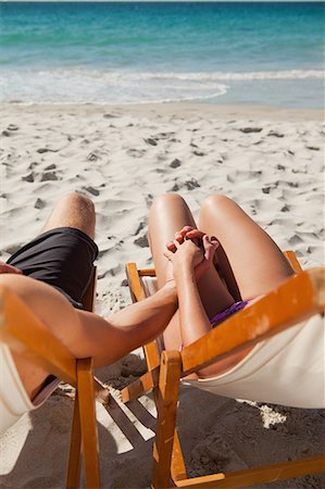 Close-up on the hands of a couple in deck chair in front of the sea Stock Photo - Premium Royalty-Free, Code: 6109-06006153