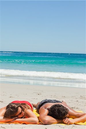 suntanning - Tanned couple sleeping on a beautiful beach with the sea in background Stock Photo - Premium Royalty-Free, Code: 6109-06006119