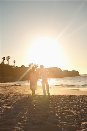 Sunset with a couple in white clothes walking on the beach Stock Photo - Premium Royalty-Free, Code: 6109-06006283