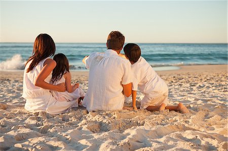 family relaxing with kids in the sun - Back view of young family enjoying the sunset on the beach Stock Photo - Premium Royalty-Free, Code: 6109-06006298