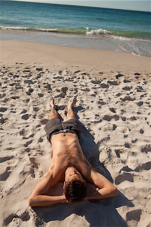 Attractive man lying on the beach in front of the sea Stock Photo - Premium Royalty-Free, Code: 6109-06006210