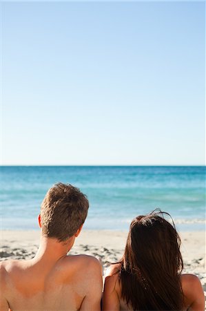 simsearch:6109-06195106,k - Rear view of a couple sitting on the sand in front of the sea Stock Photo - Premium Royalty-Free, Code: 6109-06006224