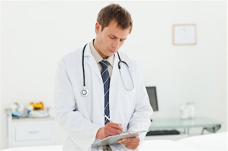 simsearch:6109-06005901,k - Male doctor in examination room taking notes Fotografie stock - Premium Royalty-Free, Codice: 6109-06006354