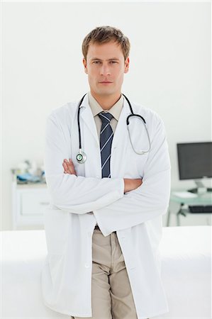 simsearch:6109-06005901,k - Serious male doctor with arms folded standing in his examination room Fotografie stock - Premium Royalty-Free, Codice: 6109-06006358