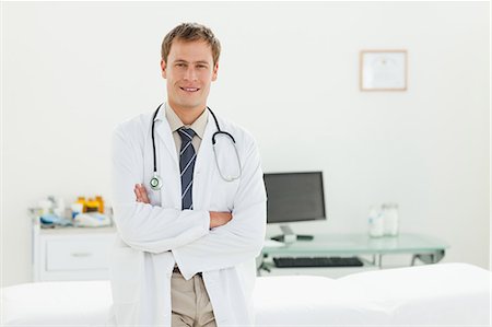 professional medical - Médecin de sexe masculin avec sa position pliée de bras dans sa salle d'examen Photographie de stock - Premium Libres de Droits, Code: 6109-06006360