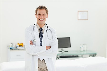 simsearch:6109-06006507,k - Smiling male doctor with his arms folded in his examination room Fotografie stock - Premium Royalty-Free, Codice: 6109-06006361