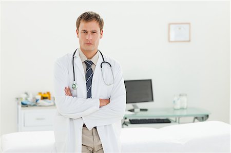 simsearch:6109-06006352,k - Male doctor standing in his examination room with his arms folded Foto de stock - Sin royalties Premium, Código: 6109-06006362