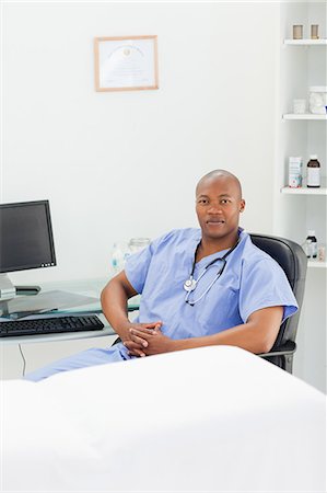 Male doctor in scrubs sitting in his examination room Stock Photo - Premium Royalty-Free, Code: 6109-06006374