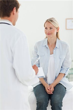 sala de exámenes - Smiling female patient sitting her doctors examination room Foto de stock - Sin royalties Premium, Código: 6109-06006379