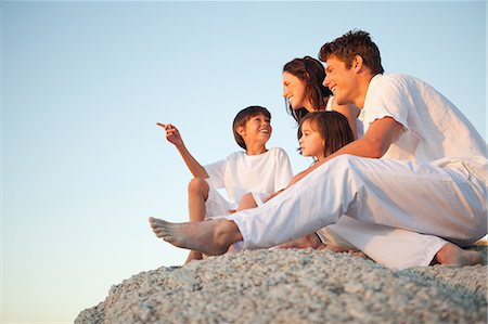 simsearch:6109-06005216,k - A family sitting on a natural rock, smiling and laughing as the son points forward. Foto de stock - Sin royalties Premium, Código: 6109-06006310
