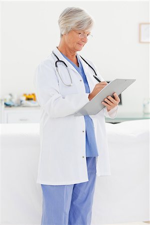 Mature doctor taking notes on a clipboard Stock Photo - Premium Royalty-Free, Code: 6109-06006317