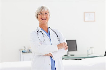 simsearch:6109-06006352,k - Smiling mature doctor with arms folded in her office Foto de stock - Sin royalties Premium, Código: 6109-06006314