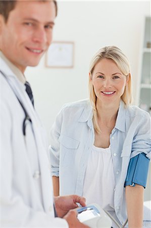 doctor with patient - Jeune femme se sa tension artérielle vérifiée souriante Photographie de stock - Premium Libres de Droits, Code: 6109-06006407