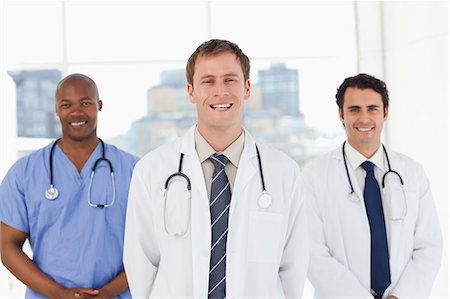simsearch:6109-06005901,k - Three smiling doctors standing in front of a window Fotografie stock - Premium Royalty-Free, Codice: 6109-06006541