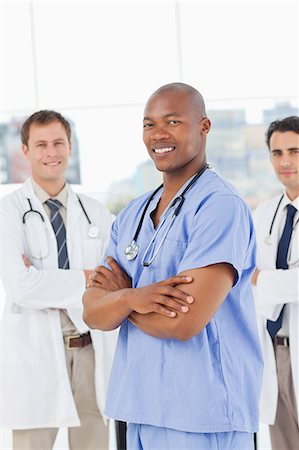 simsearch:6109-06005901,k - Three smiling doctors with their arms folded standing in front of a window Fotografie stock - Premium Royalty-Free, Codice: 6109-06006547