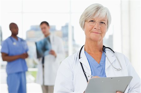 professional medical - Mature doctor with her clipboard and two colleagues behind her Stock Photo - Premium Royalty-Free, Code: 6109-06006502
