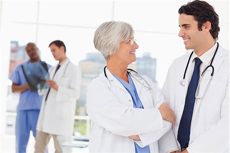 Sourire de jeune médecin avec son mentor et deux collègues derrière eux Photographie de stock - Premium Libres de Droits, Code: 6109-06006533