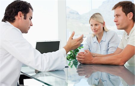 doctor at desk with patient - Side view of male doctor talking with a couple Stock Photo - Premium Royalty-Free, Code: 6109-06006650