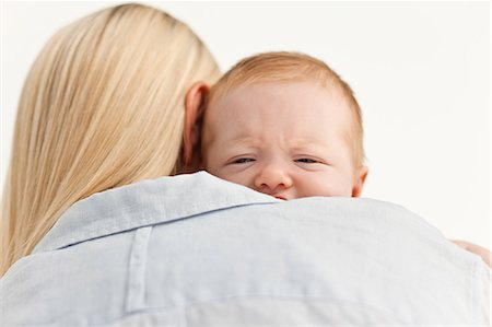 simsearch:6109-06006613,k - Sad baby being held by its mother against a white background Stock Photo - Premium Royalty-Free, Code: 6109-06006603