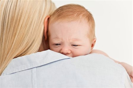 simsearch:6109-06006613,k - Sad looking baby being held by its mother against a white background Stock Photo - Premium Royalty-Free, Code: 6109-06006602