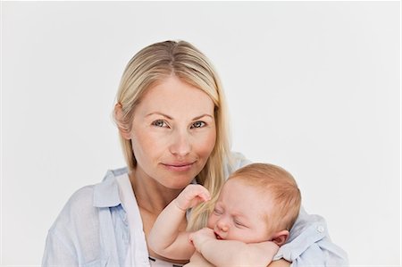 simsearch:6109-06006613,k - Mother holding her sleeping baby against a white background Stock Photo - Premium Royalty-Free, Code: 6109-06006609