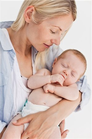 simsearch:6109-06006613,k - Mother holding her sleeping little baby against a white background Stock Photo - Premium Royalty-Free, Code: 6109-06006610